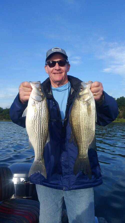 A man holding two fish in his hands.