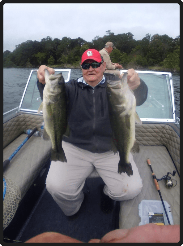 A man holding two fish on top of a boat.