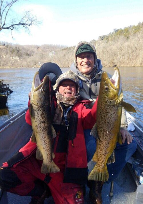 A man and woman holding up fish on a boat.