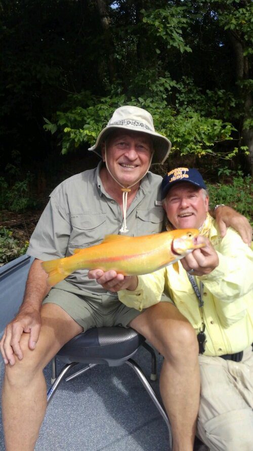 Two men sitting on a boat holding a fish.