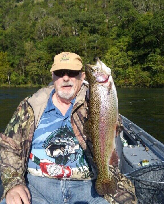 A man holding a fish in his hand while sitting on a boat.